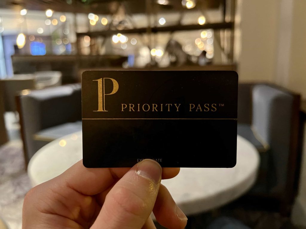 A hand holding an Amex Platinum card within an airport lounge